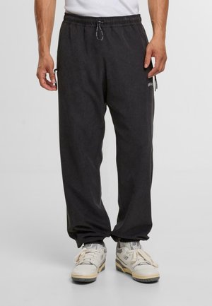 Schwarze Jogginghosen mit elastischem Bund und Kordelzug. Mit Seitentaschen und einer gebürsteten Textur für Komfort. Kombiniert mit weißen Sneakern.