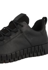 Black leather sneaker with textured surface, rounded shape, and black rubber sole featuring distinct segmented design. Laces are also black.