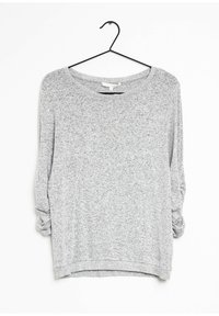 Szara bluzka z długim rękawem o luźnym kroju, z szerokim dekoltem, teksturowaną tkaniną i podwiniętymi rękawami. Zawieszona na czarnym haczyku.