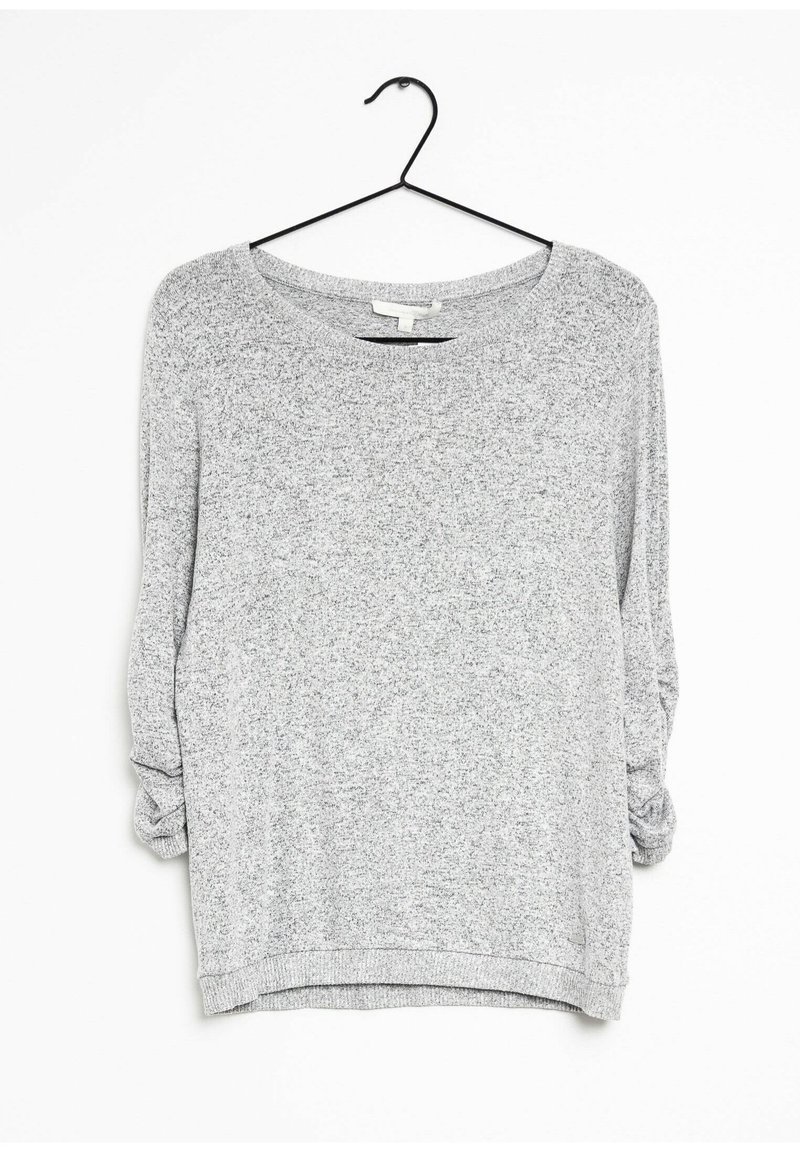 Szara bluzka z długim rękawem o luźnym kroju, z szerokim dekoltem, teksturowaną tkaniną i podwiniętymi rękawami. Zawieszona na czarnym haczyku.