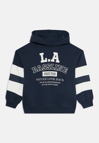 Felpa blu navy con strisce bianche sulle maniche e scritta sul fronte: L.A. Bassline, State Tour, Never Look Back, citazione motivazionale sotto.