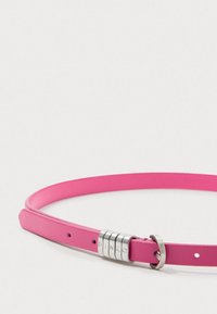 Rózsaszín bőrövet sima felülettel, ezüstszínű fémdísszel, amelybe gravírozott betűk vannak, és klasszikus csat záródással.