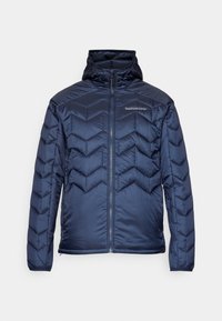 Veste matelassée marine avec un motif en chevrons, fermeture éclair et capuche. Fabriquée en tissu lisse et brillant. Dotée de poignets élastiques.
