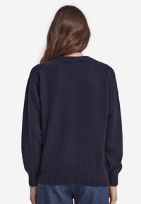 Marineblå stickad tröja med rund hals, raglanärmar och ribbad fåll. Har en mjuk textur och medeltjockt tyg.