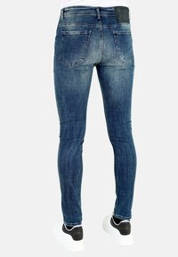 Skinny jeans in een donkere gewassen denim met een vervaagde textuur. Beschikt over twee achterzakken en een zwarte leren patch op de tailleband.