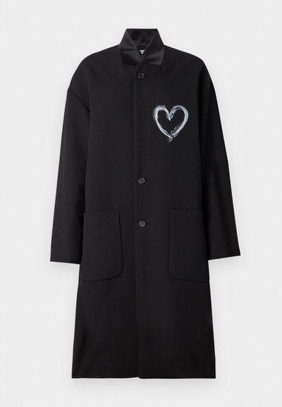 Fekete kabát szív mintával fehér festékkel, sima anyagból készült, gallérral, gombos záródással és két elülső zsebbel.