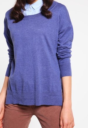 Blue knitted sweater with a round neckline and long sleeves, layered over a light blue collared shirt, made of soft fabric, smooth texture.
