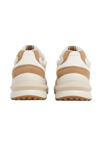 Un par de zapatillas beige y blancas con acentos de ante, vistas desde la parte posterior, mostrando suelas gruesas beige y tiradores en los talones.