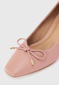 Pink leather ballet flat with a square toe, detailed with a thin bow and gold hardware accents. Features a smooth texture and cushioned interior.