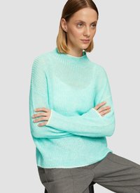 Pull léger en vert menthe, à côtes, avec un col haut et des manches longues. Le tissu semble doux et légèrement transparent, idéal pour le superposition.