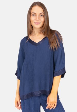 Haut bleu marine avec un col en V, des manches courtes et un tissu texturé. La bordure en satin aux manches et à l'ourlet apporte un contraste.