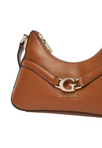 Bolso de hombro de cuero marrón con un acento de logo G dorado y cierre de cremallera, con una textura suave y diseño curvado.