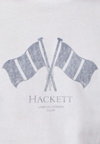Deux drapeaux croisés du club d'aviron bleu marine avec des rayures blanches et le texte « Hackett London Rowing Club » en dessous sur tissu blanc.