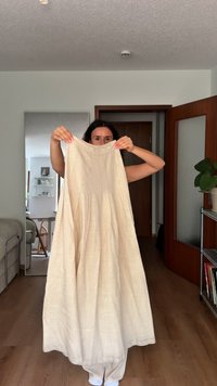 Beige liinuhame, mis on ülal hoidmiseks ja millel on sile tekstuur ning peened voldid. Kude langeb graatsiliselt, paljastades põrandani ulatuva disaini.