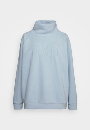 Sweat-shirt en tissu doux de couleur bleu clair avec un col haut et des manches raglan. Présente un logo "GAP" en relief sur le devant. Coupe simple et décontractée.