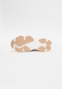 Suola di scarpa atletica bianca con un fondo in gomma marrone chiaro texturizzato e accenti bianchi, caratterizzata da un contorno design a forma di stella e scanalature.
