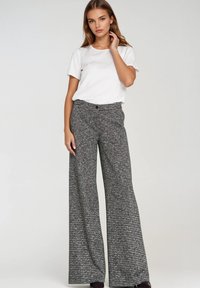 Spodnie o szerokich nogawkach w czarno-biały wzór pepitki, zestawione z gładkim białym t-shirtem. Miękka tkanina o swobodnym kroju.