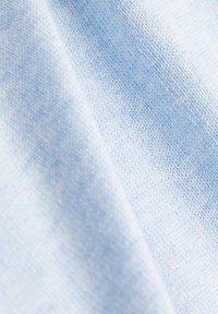 Vaaleansininen kangas, jossa pehmeä, teksturoitu kudonta, joka näyttää hienovaraisia sävyjen ja syvyyden vaihteluita koko pinnalla.