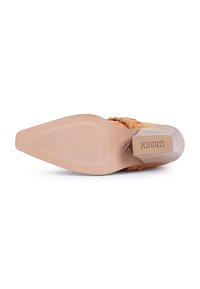 Zapato de tacón alto con parte superior de ante marrón, suela beige suave y tacón cuadrado y redondeado. Costuras decorativas a lo largo de los lados.