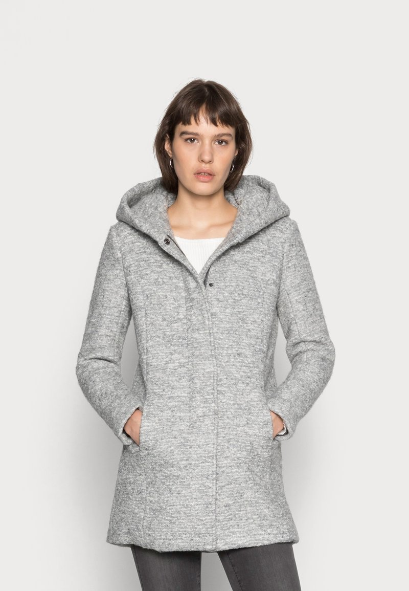 Siv obrubni plašč z teksturirano tkanino, ki ima stranske žepe, zadrgo spredaj in srednjo dolžino. Preprost in funkcionalen dizajn.