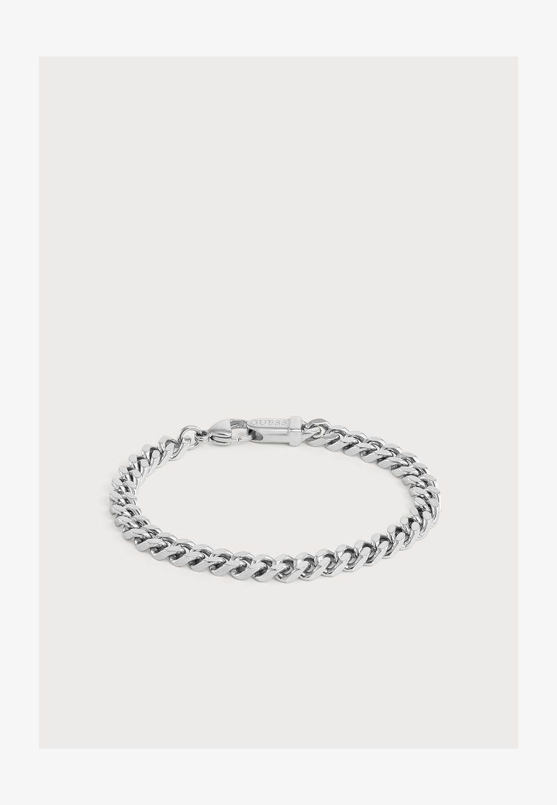 Bracelet chaîne en métal ton argenté avec un fermoir mousqueton sécurisé gravé du nom de la marque "Guess" sur fond blanc.