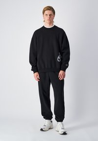 Ensemble de sweat-shirt noir et de joggeurs en mélange de coton, doté de poignets côtelés, d'un détail de logo sur le sweat-shirt et d'une coupe décontractée.