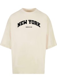 Cremefarvet bomulds-T-shirt med rund hals, korte ærmer og sort "NEW YORK" tekst i et buet design over "MERCHC•DE" logoet.