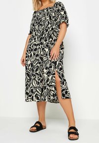 Midi šaty s květinovým vzorem v černobílé barvě, puff sleeves, skládáným živůtkem a bočním rozparkem. Nosí se s černými sandály. Texturovaná tkanina.