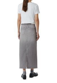 Jupe maxi en denim gris avec une coupe droite, deux poches arrière et un effet dégradé subtil. Associée à un t-shirt blanc uni.