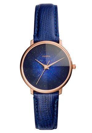 Montre ronde en or rose avec cadran bleu ciel étoilé, aiguilles dorées et bracelet en cuir bleu texturé, nom de la marque Fossil visible sur le cadran.