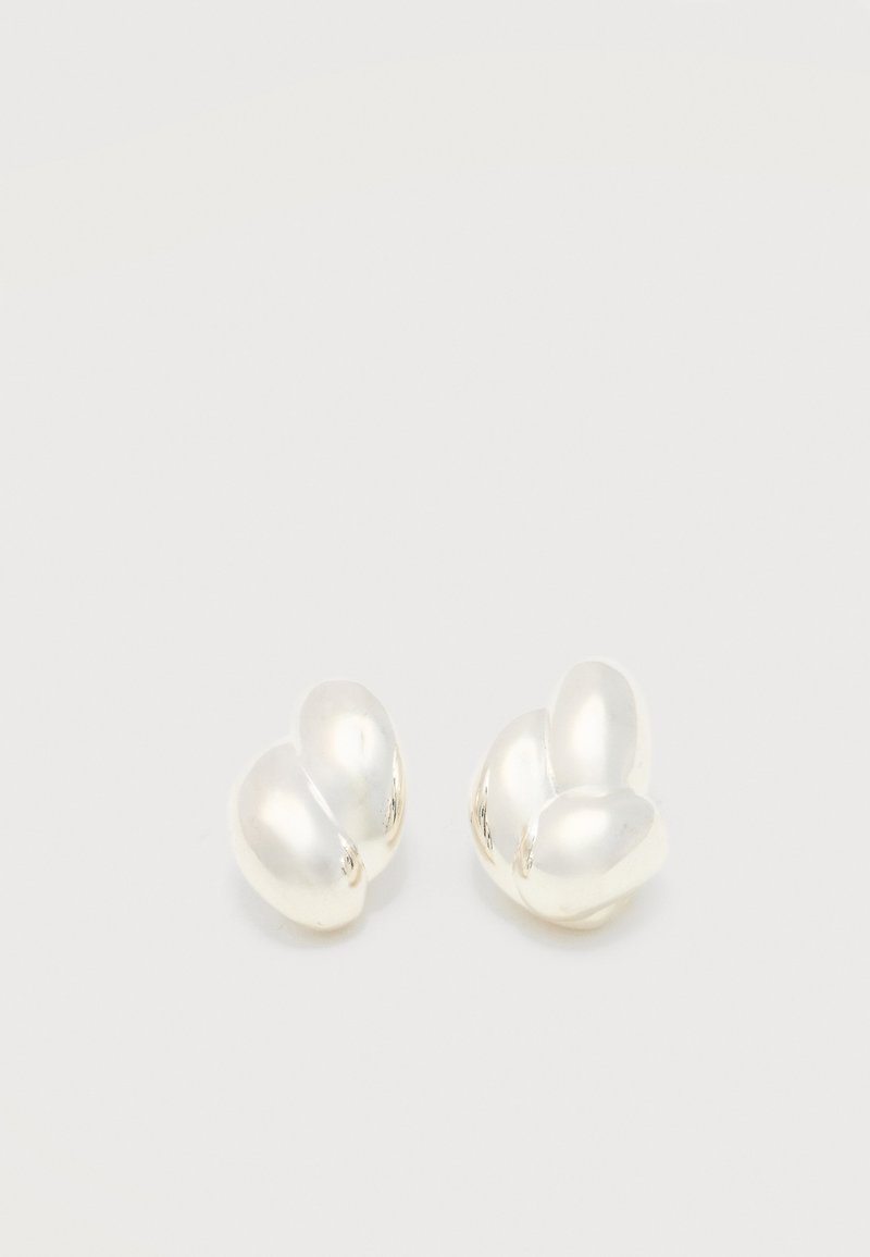 Ζευγάρι στρογγυλών σκουλαρικιών α πό λευκά μαργαριτάρια με ακανόνιστο σχήμα, σε απλό φωτεινό φόντο.