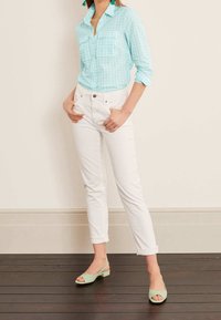 Light blue checked button-up shirt with two front pockets, paired with white fitted jeans and mint green open-toe heels.