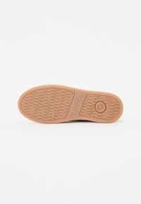 Scarpe Gabor con suola in gomma testurizzata color terra, caratterizzata da un motivo rigato e un dettaglio circolare. Il design è piatto e slanciato.