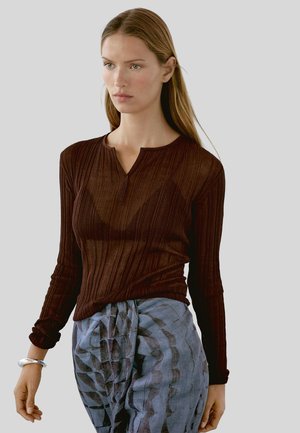 Braun gerippter Langarmoberteil mit Henley-Kragen, kombiniert mit strukturierten blau-grauen gemusterten Hosen; weicher, leichter Stoff.
