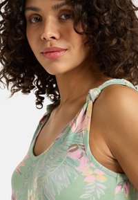 Floral tank top in green with pink and yellow accents, featuring knotted straps and a deep scoop neckline; soft, lightweight fabric.