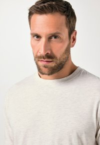 Jasnoszara koszula z długim rękawem i okrągłym dekoltem. Miękki, teksturowany materiał z delikatnym wzorem na całej powierzchni. Odpowiednia na co dzień.