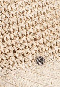Bolsa de fibra natural con una superficie texturada de punto en color blanco roto. Presenta un detalle de botón metálico para su cierre.