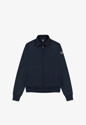 Morsko modra zip-up jakna iz mehkega materiala z stoječim ovratnikom, rebrastimi manšetami in logotipom na levem rokavu.