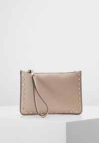 Beige pehmea nahast kott kuldsete studs-akkentidega küljel, peen randmeämpär ja ülemine tõmblukku sulgemine. Ristkülikukujuline kuju.