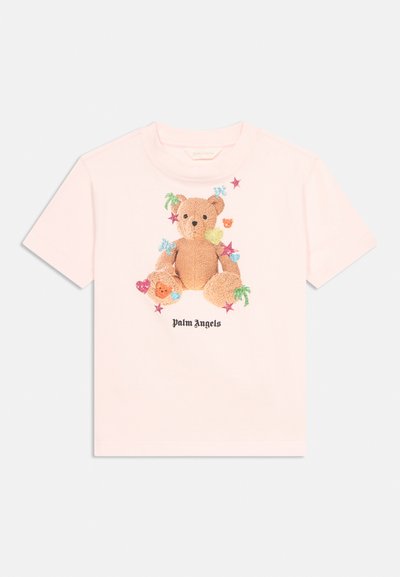 Lichtroze T-shirt met een centrale afbeelding van een teddybeer versierd met kleurrijke sterren, harten en palmbomen, met de tekst "Palm Angels" eronder.