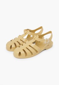 Yellow rubber sandals featuring a strappy design with cutouts, back strap, and a buckle for secure fit. Flat sole with textured surface.