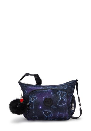 Adjustable shoulder bag with dark blue space-themed pattern, front pocket, round brand logo, and attached black fluffy keychain accessory.