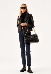 Black leather jacket with an asymmetric zipper, black ribbed turtleneck, dark jeans, and a quilted black bag with a gold chain strap.