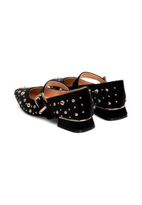 Pantofole nere in velluto con punta, dotate di borchie dorate, tacco basso a blocco e cinturini regolabili su sfondo bianco.