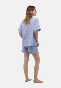 Ensemble de haut à manches courtes et de shorts rayés bleus et blancs, avec des points brodés, coupe décontractée et des pipings contrastants le long des bords.