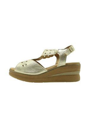 Sandalia wedge de cuero dorado con detalles recortados y una correa en el tobillo con hebilla. Parte superior texturizada y suela de plataforma marrón en contraste.