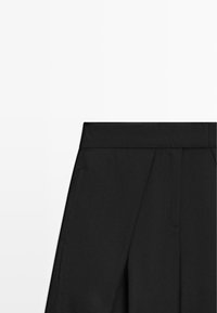 Pantaloni neri a vita alta con pieghe e tasche laterali su sfondo bianco.