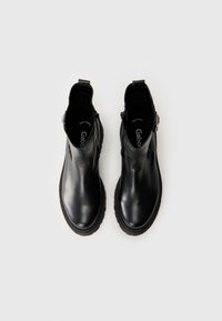 Botas de cuero negras hasta el tobillo con un acabado suave, cremalleras laterales y una suela texturizada. Punta ligeramente redondeada y elementos de diseño minimalistas.