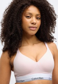 Ροζ ανοιχτό ροζ μπραλέτα με λεία υφή, λαιμόκοψη V, χοντρή μαύρη και λευκή ελαστική ταινία με το λογότυπο "Calvin Klein".