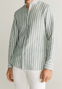 Camisa de mangas largas a rayas verdes y blancas con cuello tipo banda, cierre de botones en la parte delantera y rayas en contraste en los puños. Tejido de mezcla de lino casual.